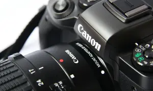 Zbliżenie na czarny aparat Canon z obiektywem i paskiem.