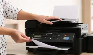 Ręce kładą papier na drukarce atramentowej czy laserowej, gotowe do drukowania.