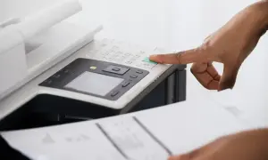 Dłoń naciska zielony przycisk na drukarce Epson, która drukuje na różowo.
