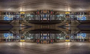 Nocne miasto z żółtym tramwajem i ludźmi, tworzące symetryczną, lustrzaną kompozycję.
