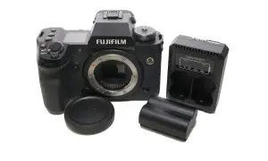 Aparat Fujifilm xh2s z obiektywem, ładowarką i bateriami.
