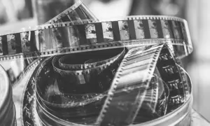 Zwoje taśmy filmowej do analoga, pełne klatek z przeszłości, tworzą artystyczny bałagan w metalowym pudełku.