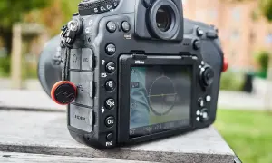 Nikon z funkcją SnapBridge po polsku. Aparat leży na drewnianym stole, w tle zieleń.