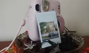 Różowy Instax Mini 11 z wywołanym zdjęciem domu i samochodu. Dowiedz się, jak robić zdjęcia Instax!