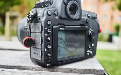 Nikon z funkcją SnapBridge po polsku. Aparat leży na drewnianym stole, w tle zieleń.