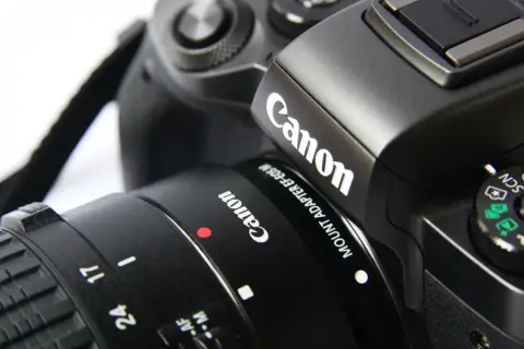 Zbliżenie na czarny aparat Canon z obiektywem i paskiem.
