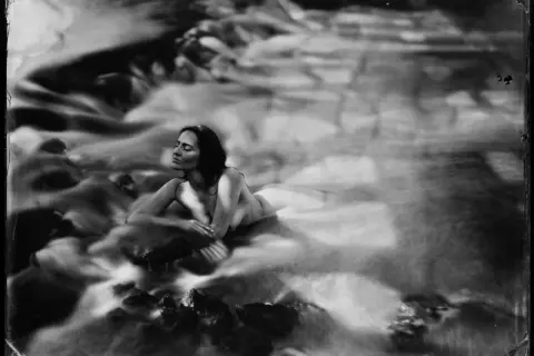 Kobieta w wodzie, z zamkniętymi oczami, otoczona płynącą wodą. Efekt mokry kolodion nadaje zdjęciu eteryczny, senny charakter.