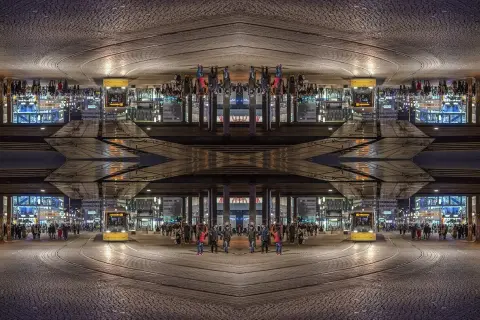 Nocne miasto z żółtym tramwajem i ludźmi, tworzące symetryczną, lustrzaną kompozycję.