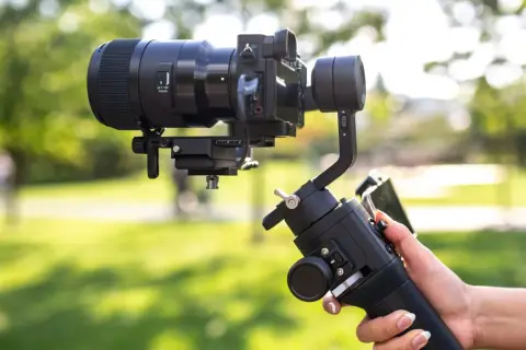 Profesjonalny gimbal stabilizuje aparat z obiektywem, zapewniając płynne ujęcia. To właśnie gimbal co to za urządzenie, które ułatwia filmowanie.