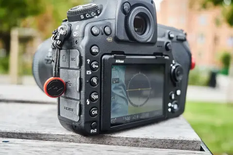 Nikon z funkcją SnapBridge po polsku. Aparat leży na drewnianym stole, w tle zieleń.