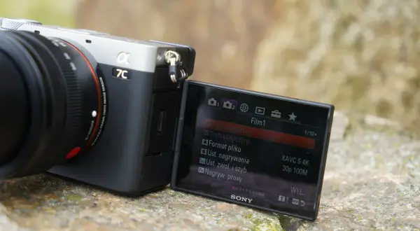 Aparat Sony a7c z obiektywem, na ekranie widoczne menu filmowania z ustawieniami XAVC S 4K.
