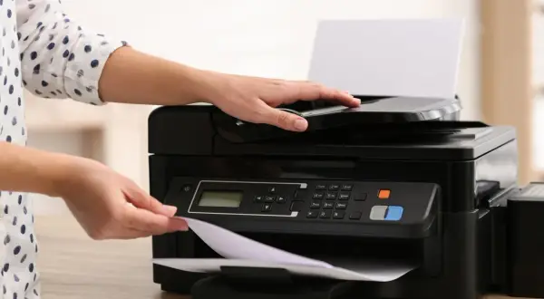 Ręce kładą papier na drukarce atramentowej czy laserowej, gotowe do drukowania.