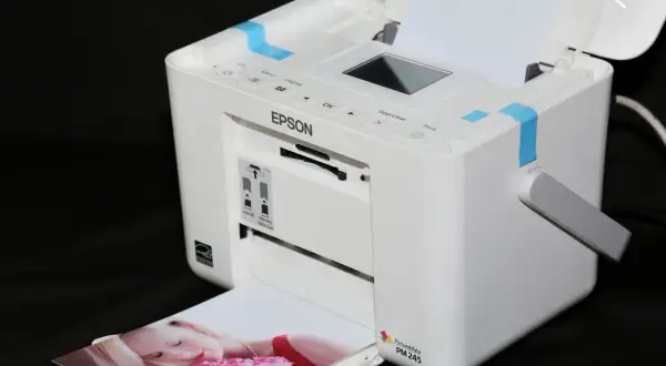 Biała drukarka Epson PictureMate PM 245 drukuje zdjęcie kobiety z różami. Szukasz, jaka drukarka najtańsza w eksploatacji?