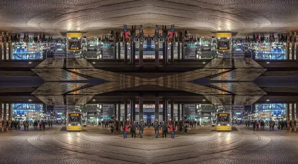Nocne miasto z żółtym tramwajem i ludźmi, tworzące symetryczną, lustrzaną kompozycję.