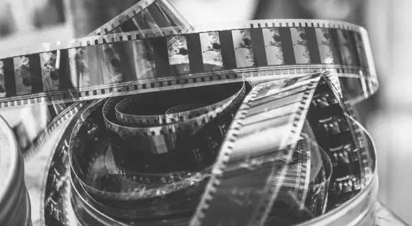 Zwoje taśmy filmowej do analoga, pełne klatek z przeszłości, tworzą artystyczny bałagan w metalowym pudełku.
