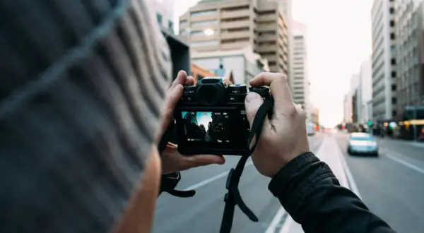 Fotografia reportażowa uchwycona przez osobę w czapce, trzymającą aparat i kadrującą miejski krajobraz.