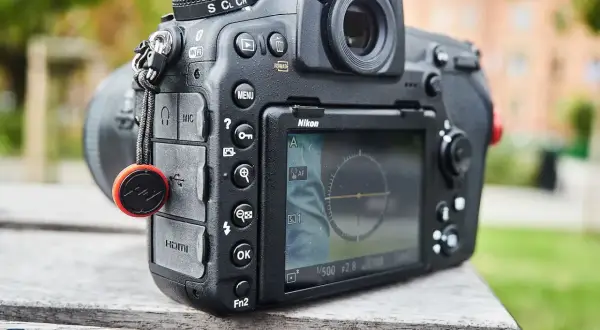 Nikon z funkcją SnapBridge po polsku. Aparat leży na drewnianym stole, w tle zieleń.