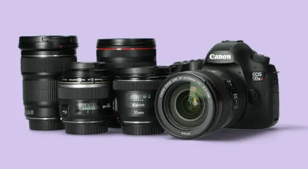 Kilka obiektywów Canon i korpus aparatu EOS 5Ds R na jasnofioletowym tle.