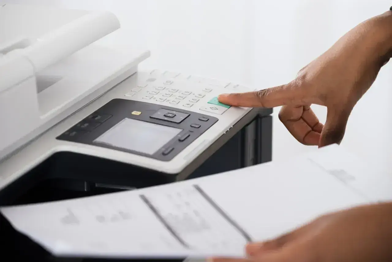 Dłoń naciska zielony przycisk na drukarce Epson, która drukuje na różowo.