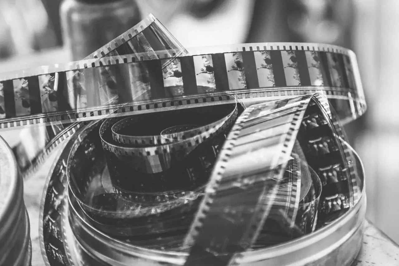 Zwoje taśmy filmowej do analoga, pełne klatek z przeszłości, tworzą artystyczny bałagan w metalowym pudełku.