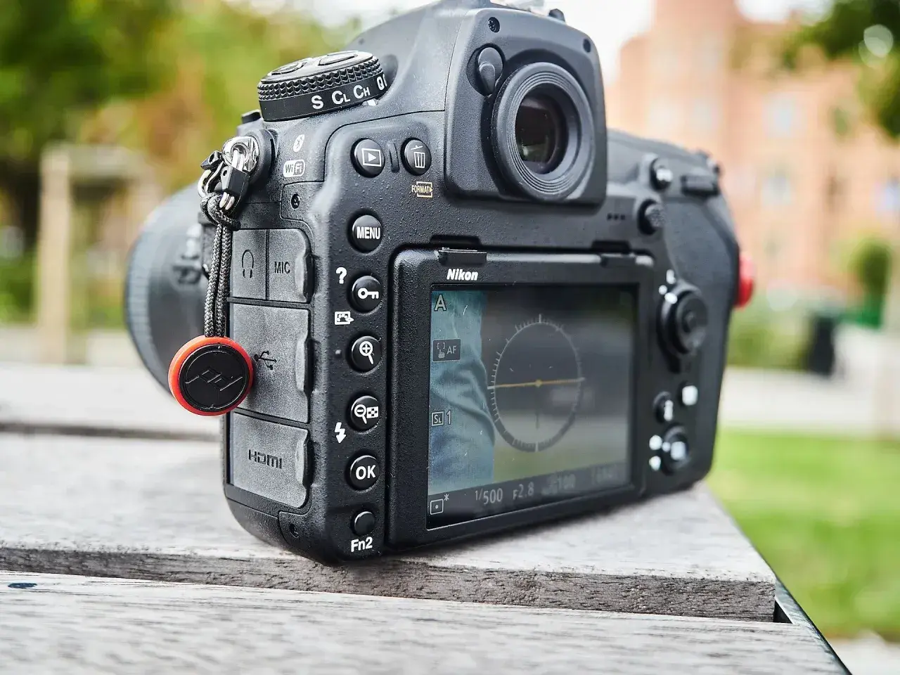Nikon z funkcją SnapBridge po polsku. Aparat leży na drewnianym stole, w tle zieleń.
