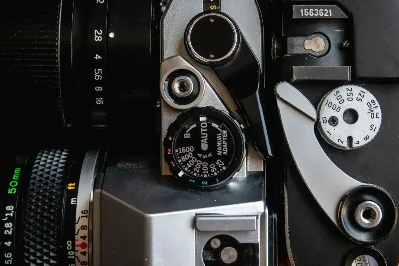 Zbliżenie na detale klasycznego filmu do analoga: pokrętła przysłony, czasu naświetlania i dźwignię naciągu.