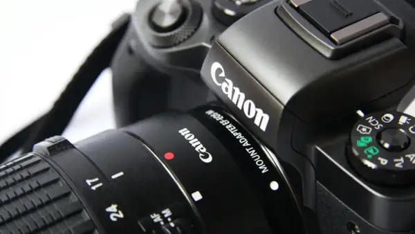 Zbliżenie na czarny aparat Canon z obiektywem i paskiem.