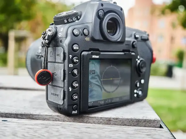 Nikon z funkcją SnapBridge po polsku. Aparat leży na drewnianym stole, w tle zieleń.